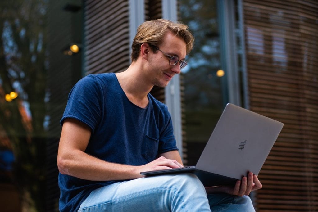 Man smiling while using his laptop.