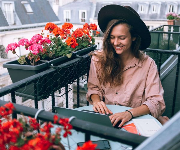 Woman smiling working with her laptop at a balcony