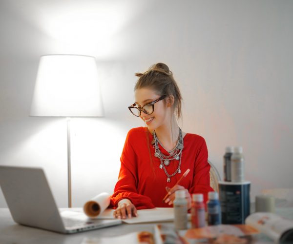 Woman with red shit working remotely with her laptop